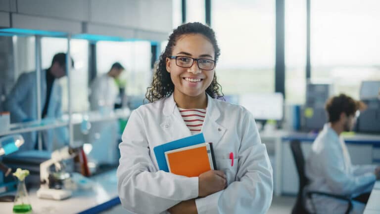 young female scientist in lab wearing white coat and holding books