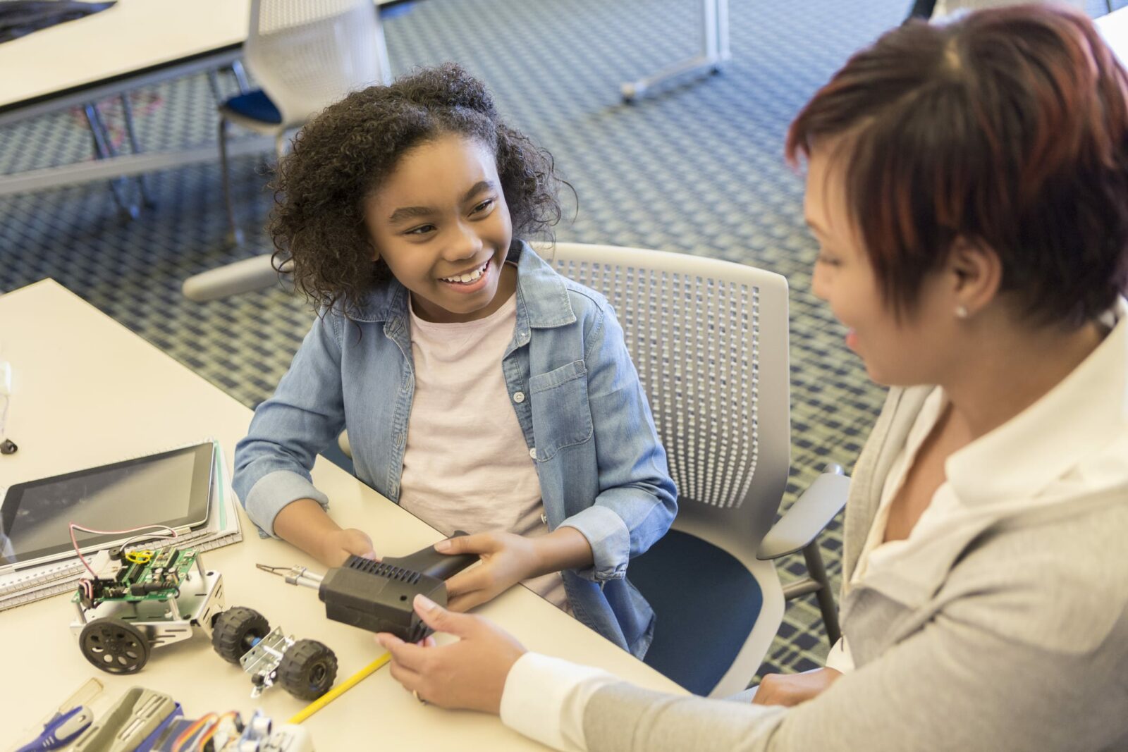 Teacher helps young student build robot