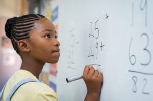 Young girl doing math on white board