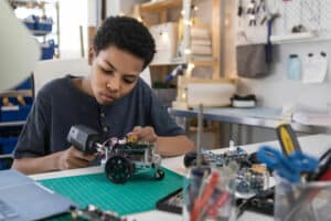 teen boys solders wires to build a robot