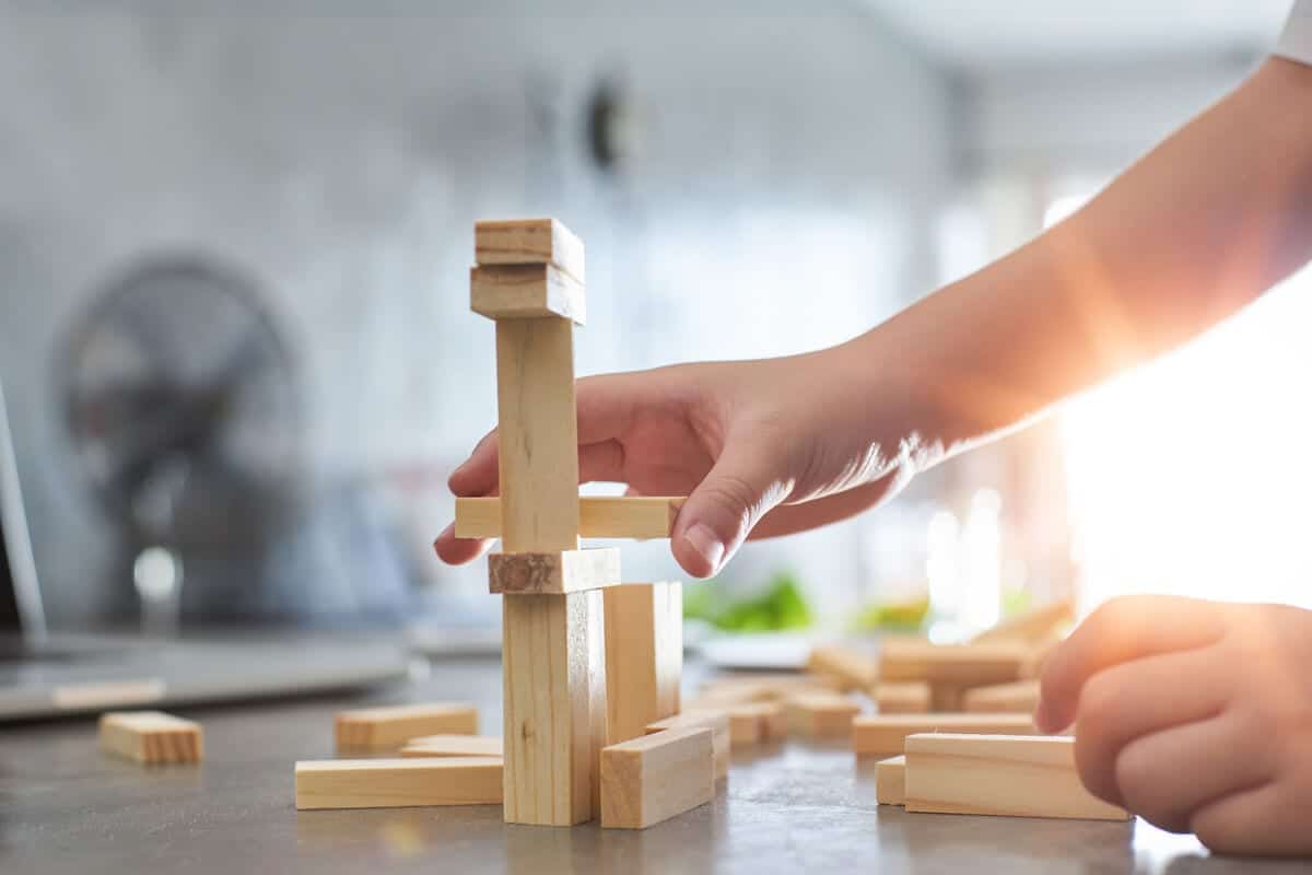 Hand_of_kid_playing_a_blocks_wood_tower_game_of_architectural_project