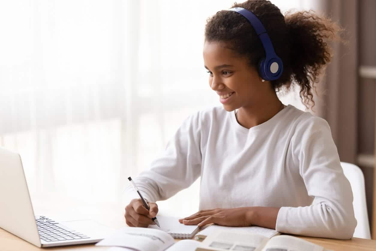 happy teen engaging with a class and doing work on her laptop