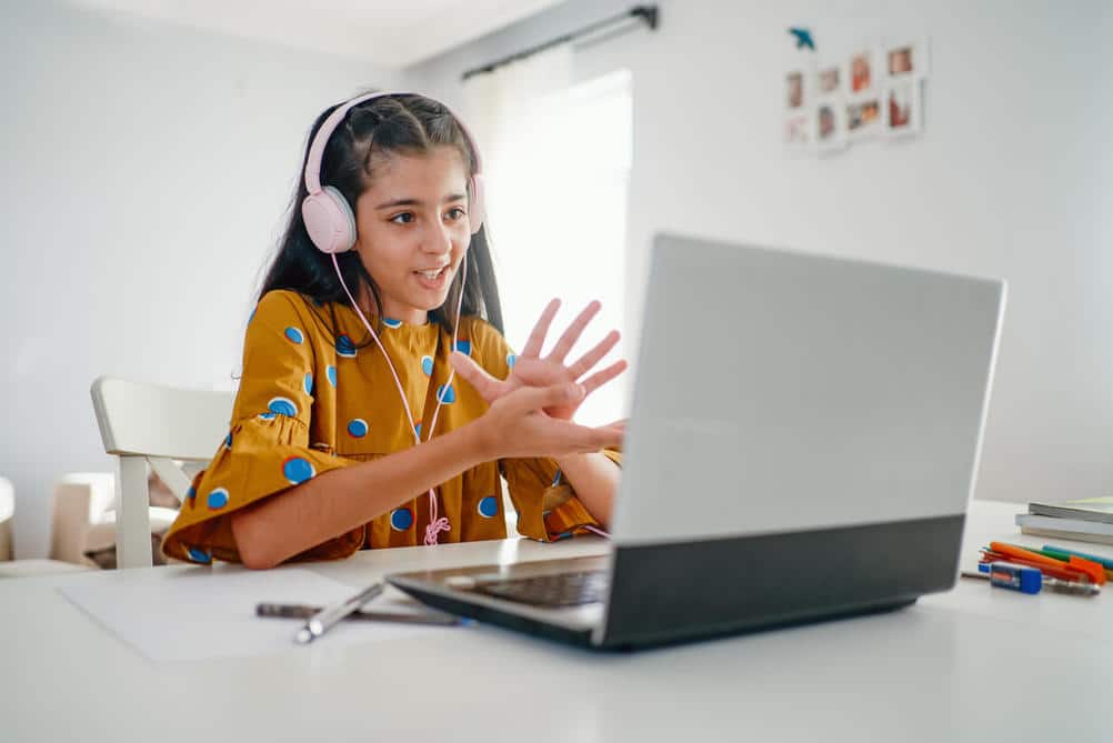 Teenage_girl_with_headphones_talking_and_working_on_laptop