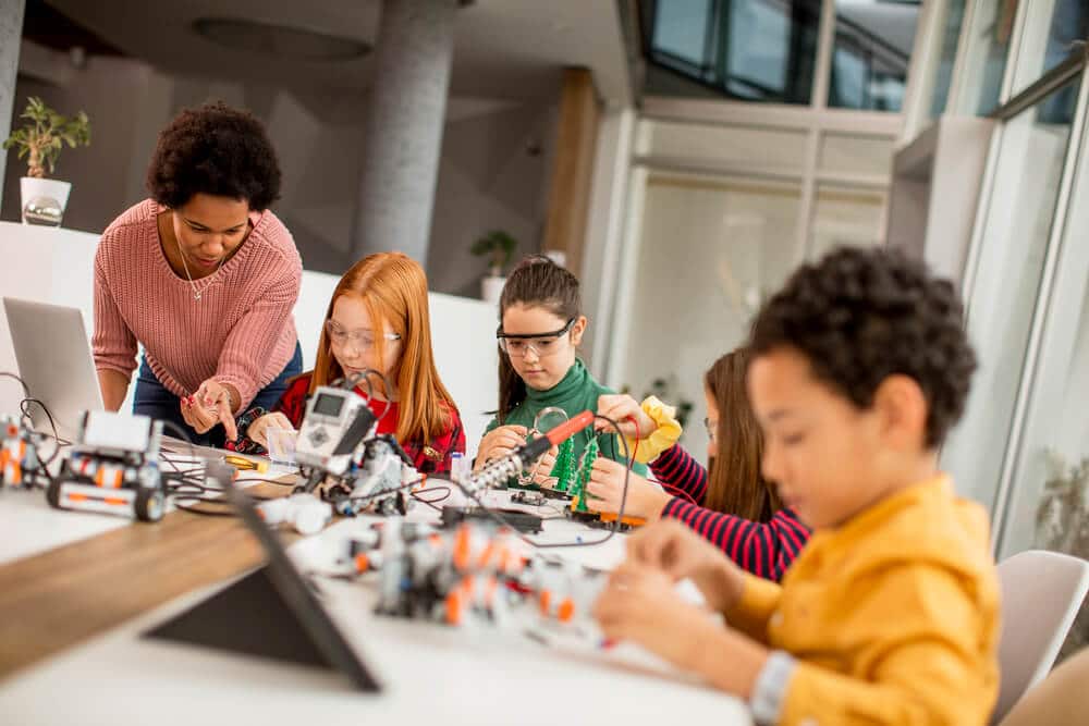 Group of kids working on robotics projects with teacher