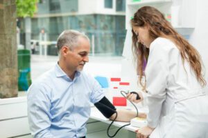 young female student using a blood pressure gauge on a mature man