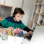 4th grade boy taking a virtual class at home on computer