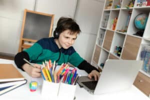 4th grade boy taking a virtual class at home on computer