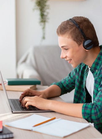 cheerful student with headset typing on laptop