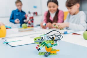 Multicolored handmade robot at desk with school children