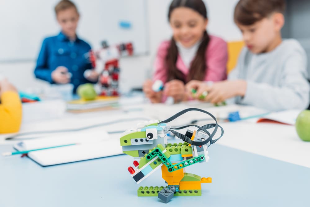 Multicolored handmade robot at desk with school children