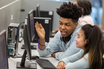 male computer student helps female student in lab