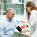 young female student using a blood pressure gauge on a mature man