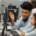 male high school student helping a student in the computer lab