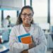 young female scientist in lab wearing white coat and holding books